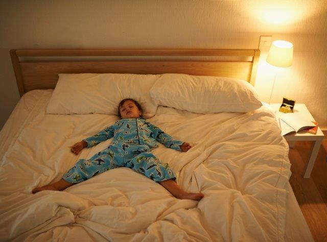 Child laying in a big bed sleeping 