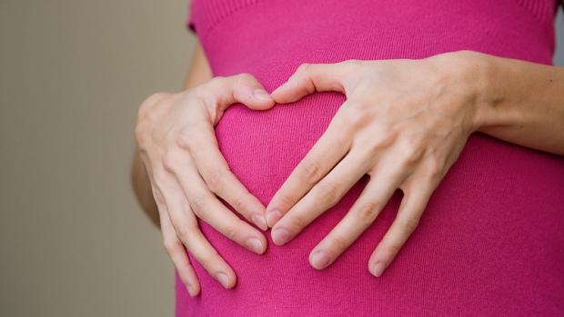 Pregnant worman with hands in heart shape over belly